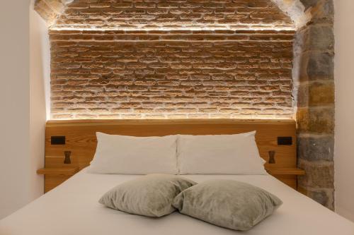 a bedroom with a brick wall and a bed with pillows at San Nicolò Suites in Trieste