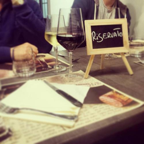 una mesa con un cartel y una copa de vino en La Piccola Locanda, en Chiusi