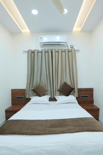 Un dormitorio con una cama blanca con cortinas. en SEVEN HILLS Guest House, en Akalkot