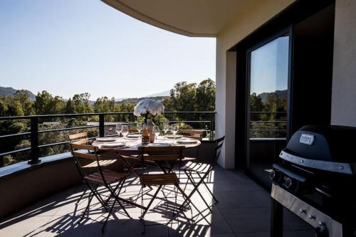 une table et des chaises sur un balcon avec vue dans l'établissement Joséphine - Appt vue exceptionnelle Porto-Vecchio, à Porto-Vecchio