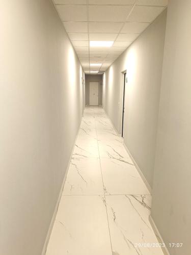 a long corridor with white walls and a white tile floor at Residenza delle Nazioni in Gatteo a Mare