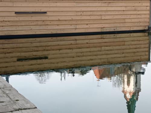 a wooden building with its reflection in the water at Drei-Seiten-Hof Étable mit Schwimmteich und Klimanlage in Fuchshain