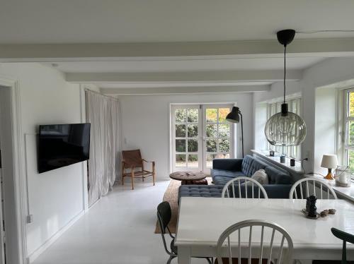 a living room with a couch and a table at Charmerende lejlighed på landet med privat skov in Bjergby