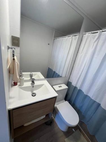 Un baño con un lavabo blanco y un inodoro. en Acogedor y nuevo departamento para ti en Coquimbo, en Coquimbo