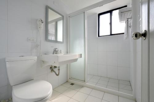 a white bathroom with a toilet and a sink at C U Hotel Taichung in Taichung