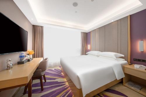 a hotel room with a white bed and a desk and a tv at Guangzhou Baiyun Airport Yunzhi Hotel near Terminal One - Complimentary Shuttle Bus between hotel to Canton Fair Complex during Canton Fair in Guangzhou