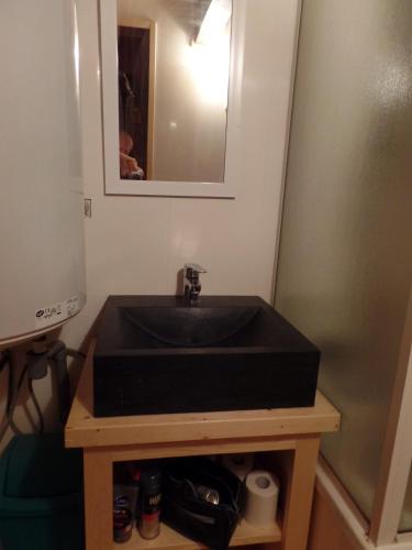 une salle de bain avec un lavabo noir et un miroir dans l'établissement Le Petit Paddock, à Saint-Gervais-les-Bains