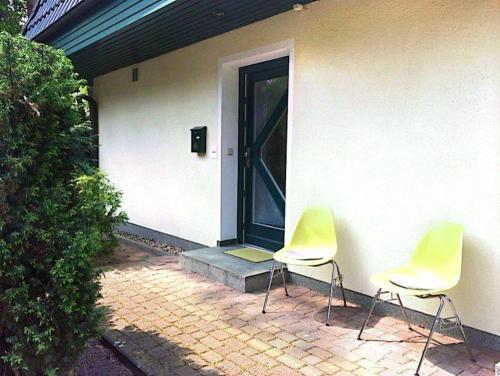 due sedie sedute fuori da una casa con una porta di Ferienwohnung Achterhuus a Kölpinsee auf Usedom