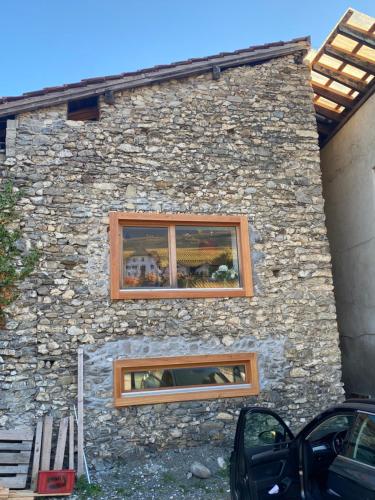 two windows on the side of a stone building at Appartement Rosa au coeur des 4 Vallées in Conthey