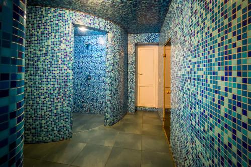 Un baño con paredes de azulejos azules y una puerta blanca. en Арніка, en Synevyrsʼka Polyana