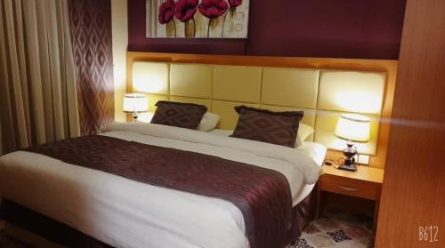 een hotelkamer met een groot bed met 2 lampen bij شقق فندقية التلال in Mekka