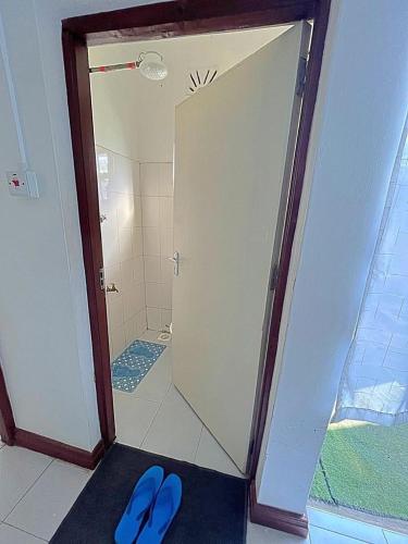 a bathroom with a shower with blue shoes on the floor at Homely apt 1 (one) in Kisumu