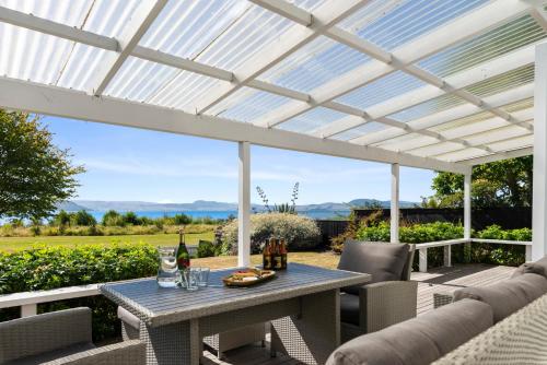 a white pergola on a patio with a table and chairs at Ngongotaha Lakeside Home in Rotorua