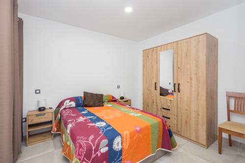 Un dormitorio con una cama y un armario de madera. en Lightbooking Apartamento con terraza en playa de Arinaga, en Agüimes