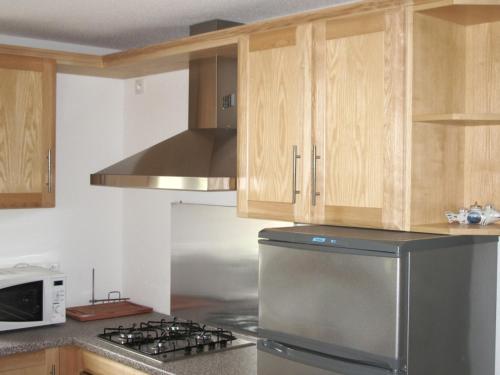 une cuisine avec un réfrigérateur en acier inoxydable et des armoires en bois dans l'établissement l'escapade, à Saint-Étienne-lès-Remiremont