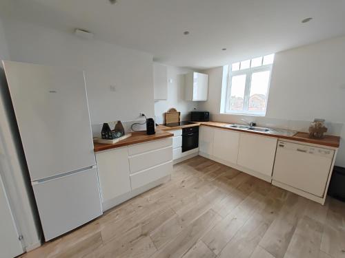 a kitchen with white cabinets and a wooden floor at " Belle " Étoile in Bailleul