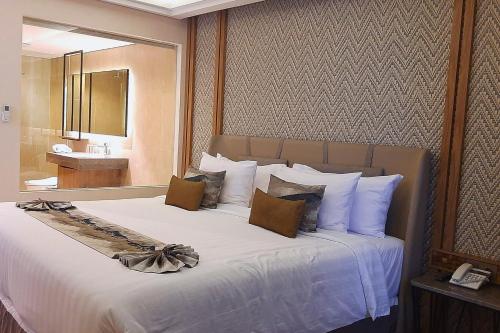 Schlafzimmer mit einem großen weißen Bett und einem Spiegel in der Unterkunft Paradise Island 1 BR Beach View NE33 in Teluk Nara