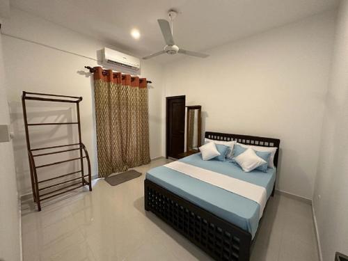 a bedroom with a bed with blue sheets and a fan at highway reach Layathraa in Kaduwela