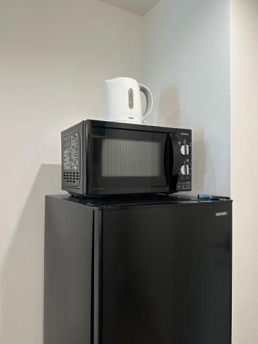 a microwave sitting on top of a refrigerator at Hoshino Stay 2 Near Namba 3-Min Walk to Station in Osaka