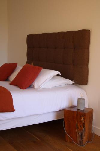 a bed with white sheets and red pillows next to a table at Casa Santa Lucia in Bocognano