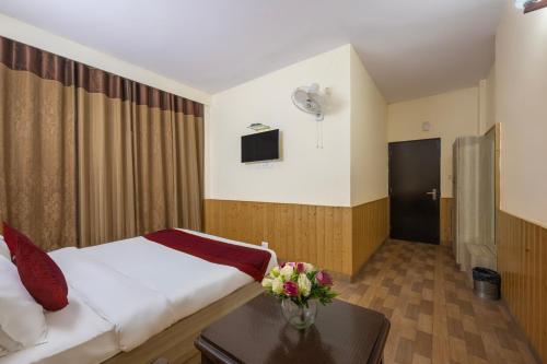 a hotel room with a bed and a table with flowers at Seven Hills Shimla by Him Haults Hospitality in Shimla