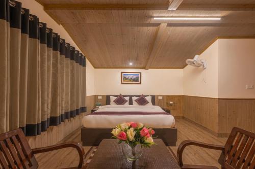 a bedroom with a bed and a table with flowers on it at Seven Hills Shimla by Him Haults Hospitality in Shimla