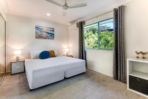 a bedroom with a white bed and a window at Sunset Waters Apartments in Hamilton Island