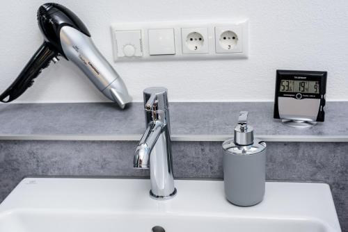 a sink with a faucet and a clock on a counter at Berg Fux - Ferienwohnung Alfred der Büffel in Sonthofen