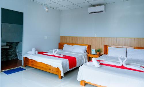 a bedroom with two beds with red and white sheets at Cali Hill Resort in Phu Quoc