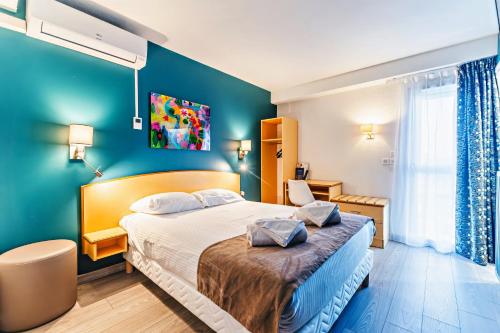 a bedroom with a bed and a blue wall at The Originals City, H&ocirc;tel &Eacute;clipse, Lyon Est in D&eacute;cines-Charpieu