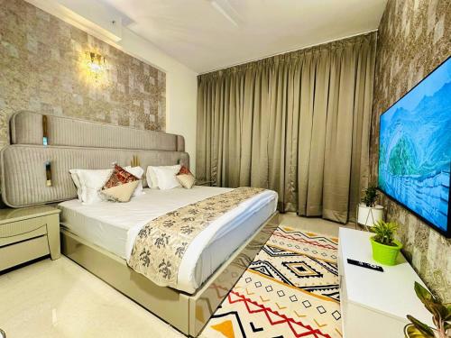 una camera con un grande letto e una TV a schermo piatto di Tranquil Manor With Swimming Pool a Lucknow