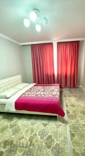 een slaapkamer met een groot bed met rode gordijnen bij ЖК Алмалы in Alma-Ata