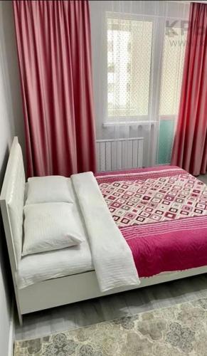 een slaapkamer met een bed met rode gordijnen bij ЖК Алмалы in Alma-Ata