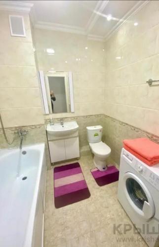 een badkamer met een wastafel en een wasmachine bij ЖК Алмалы in Alma-Ata