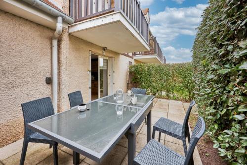 Une table à manger et des chaises sont disponibles sur la terrasse. dans l'établissement Blue World - Appt avec terrasse, à Merville-Franceville-Plage