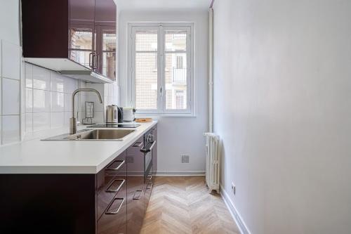 une cuisine blanche avec un évier et une fenêtre dans l'établissement Apartment next to Palais des Congrès - Neuilly - II, à Neuilly-sur-Seine
