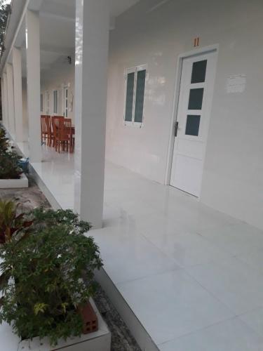 un pasillo blanco con una puerta y algunas plantas en Nhà Nghỉ Tốt Hơn en Phu Quoc