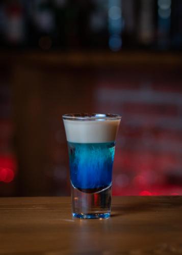 a blue drink in a glass sitting on a table at VinoOdor - ვინოოდორ in Tʼelavi
