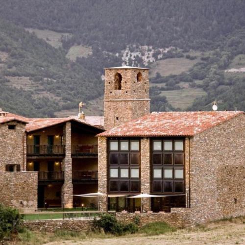 duży ceglany budynek z wieżą na górze w obiekcie LA HOSTERIA DE TOLORIU, el alt Urgell w mieście Toloríu