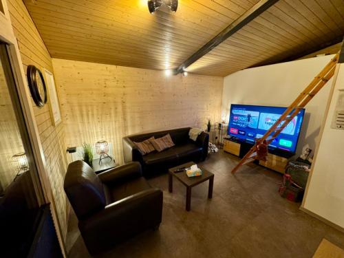 a living room with a couch and a flat screen tv at Ferienwohnung Brunni-Lodge am Grossen Mythen in Alpthal