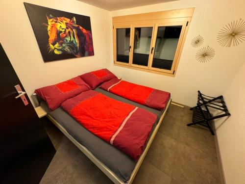 uma cama com lençóis vermelhos num quarto em Ferienwohnung Brunni-Lodge direkt am Grossen Mythen em Alpthal