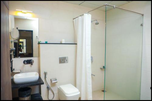 a bathroom with a shower and a toilet and a sink at The Byke Suraj Club, Junagadh in Junagadh