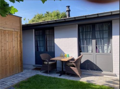 a patio with a table and chairs in front of a house at Ken 't Gat Bie&Bie in Maldegem