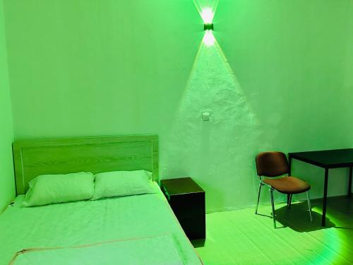 1 dormitorio con una pared verde, cama y escritorio en Big bedroom in apartment sharing washroom, en Sharjah