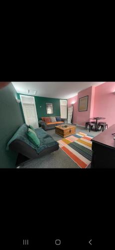 een woonkamer met roze en groene muren en een bank bij 205a Monton Road in Manchester