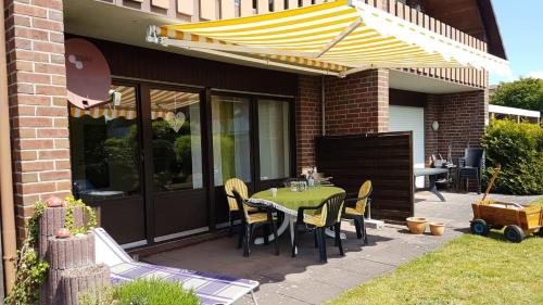 a patio with a table and chairs under an umbrella at Ferienwohnung Hoffmann, FeWo Vermittlung Nordsee in Dangast