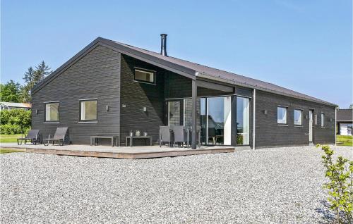 a black house with glass doors on a gravel yard at Four-Bedroom Holiday Home In Haderslev in Haderslev