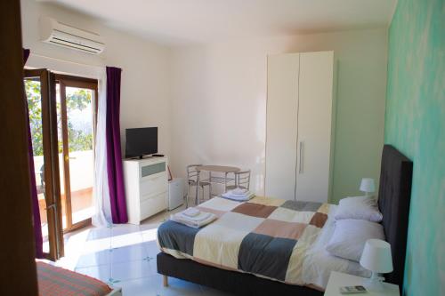 1 dormitorio con 1 cama, TV y ventana en B&B Villa Setharè, en Salerno