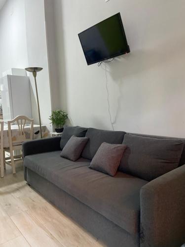 ein Wohnzimmer mit einem Sofa und einem Flachbild-TV an der Wand in der Unterkunft Apartamentos Redondela in Madrid