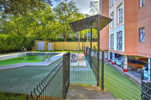 a fence around a swimming pool in front of a building at Precioso piso residencial in Seville
